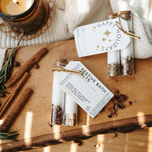 Load image into Gallery viewer, Spices and bath salts on a wooden surface with a candle and decorative elements. Christmas scent bath salts