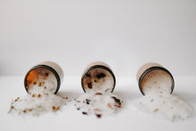 Load image into Gallery viewer, Herbal Epsom Bath Salts in amber jars. The bath salts are spilled out and there are eucalyptus leaves, chamomile flowers, lavender buds and rose petals