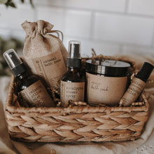 Load image into Gallery viewer, The spa gift set which includes a eucalyptus shower spray, organic lavender oatmeal bath soak, headache relief roller, essential oil & herb revive bath soak and a relaxing pillow mist. The set is on a blanket inside of a basket in front of subway tile.