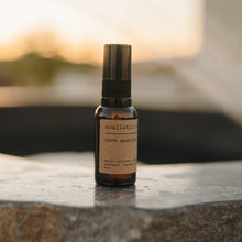 Load image into Gallery viewer, Arnica and essential oil sore muscle relief bottle on a stone natural hot springs tub outside.