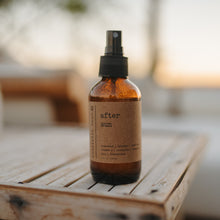 Load image into Gallery viewer, After Sun Aloe Vera Sunburn Spray 4 oz amber spray bottle sitting outside on a wooden lounge chair.
