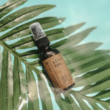Load image into Gallery viewer, After Sun Aloe Vera Sunburn Spray 2 oz amber spray inside of a pool of water balancing on a palm leave
