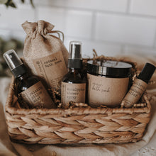 Load image into Gallery viewer, The spa gift set which includes a eucalyptus shower spray, organic lavender oatmeal bath soak, headache relief roller, essential oil &amp; herb revive bath soak and a relaxing pillow mist. The set is on a blanket inside of a basket in front of subway tile.
