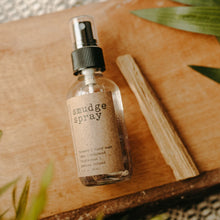 Load image into Gallery viewer, Amethyst Infused Essential Oil Smudge Spray next to a palo santo stick on a wooden block .
