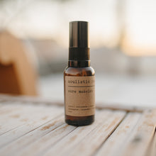 Load image into Gallery viewer, Arnica and essential oil sore muscle relief bottle on a table outside.
